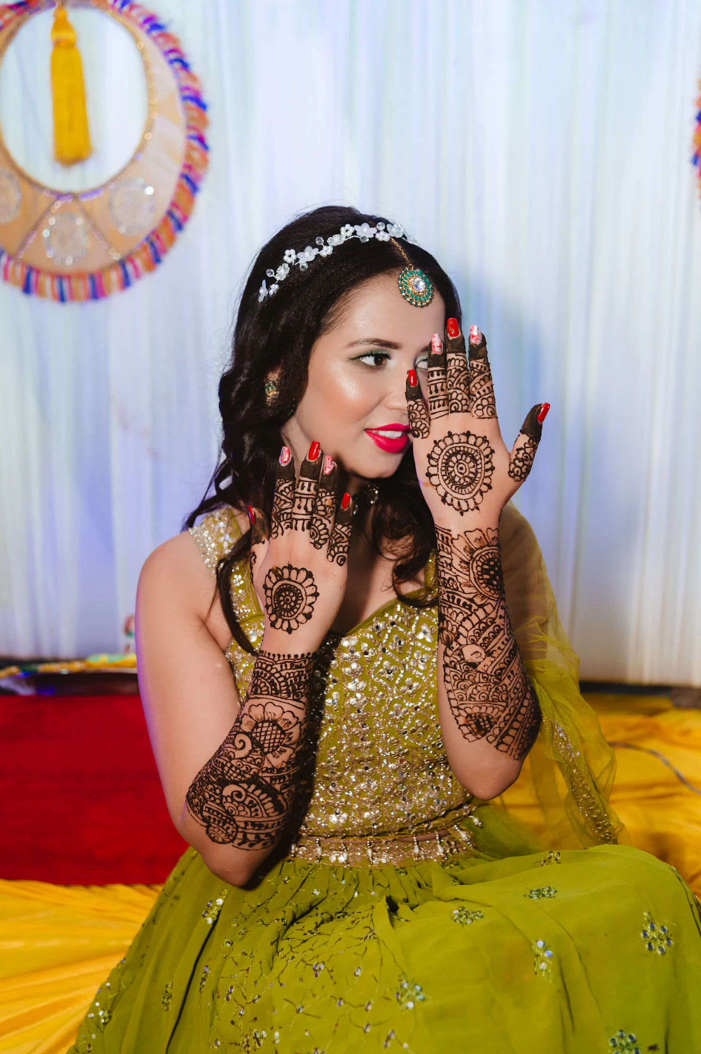 A bride in a green dress showing her mehndi palms.