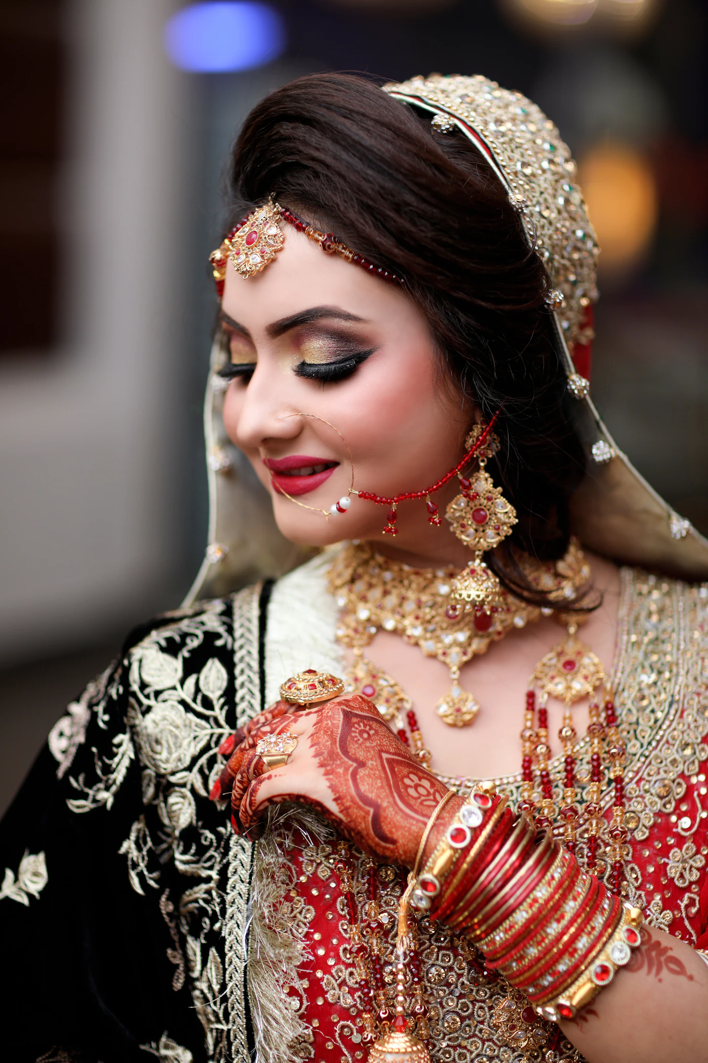 A bride in black and gold with red bangles and jewellery.